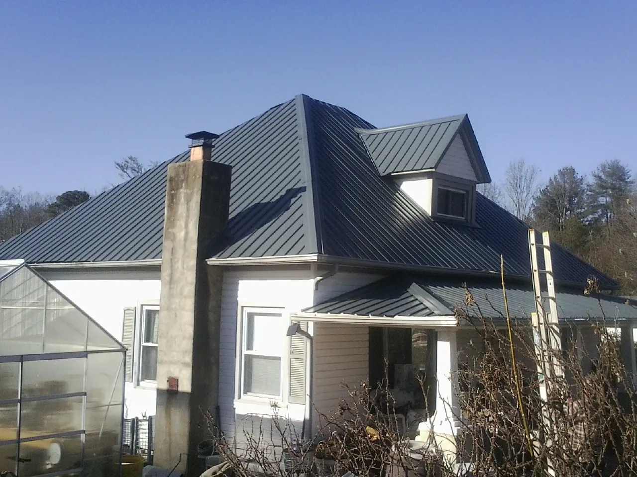 Dark blue standing seam metal roof on a white farmhouse with dormer — Slate & Tile Roof Repair by Roofing Brothers in Oroville