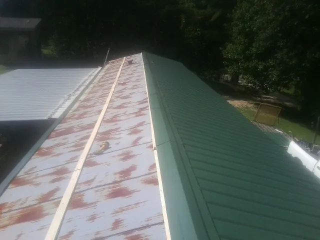 Old rusted panels beside newly installed green metal roofing — Wind Damage Roof Repair by Roofing Brothers in Oroville