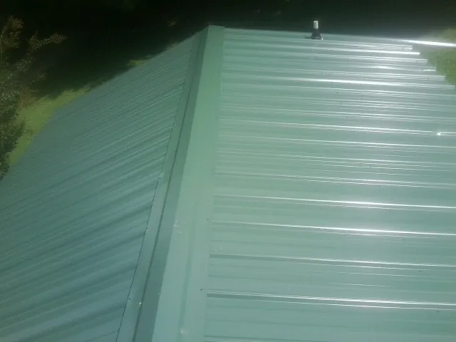 New green metal panels meeting at the ridge of a roof — Flat Roof Repair work by our crew in Oroville