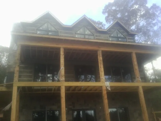 Dormers and porch framing on a large log home under construction — Roof Coating work by our crew in Oroville