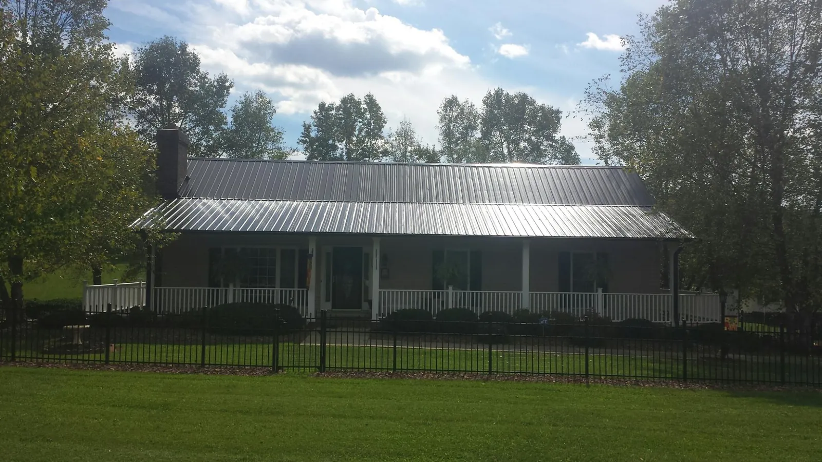 Gray metal roof on a brick ranch with a full width front porch — Gutter Guard Installation work by our crew in Oroville