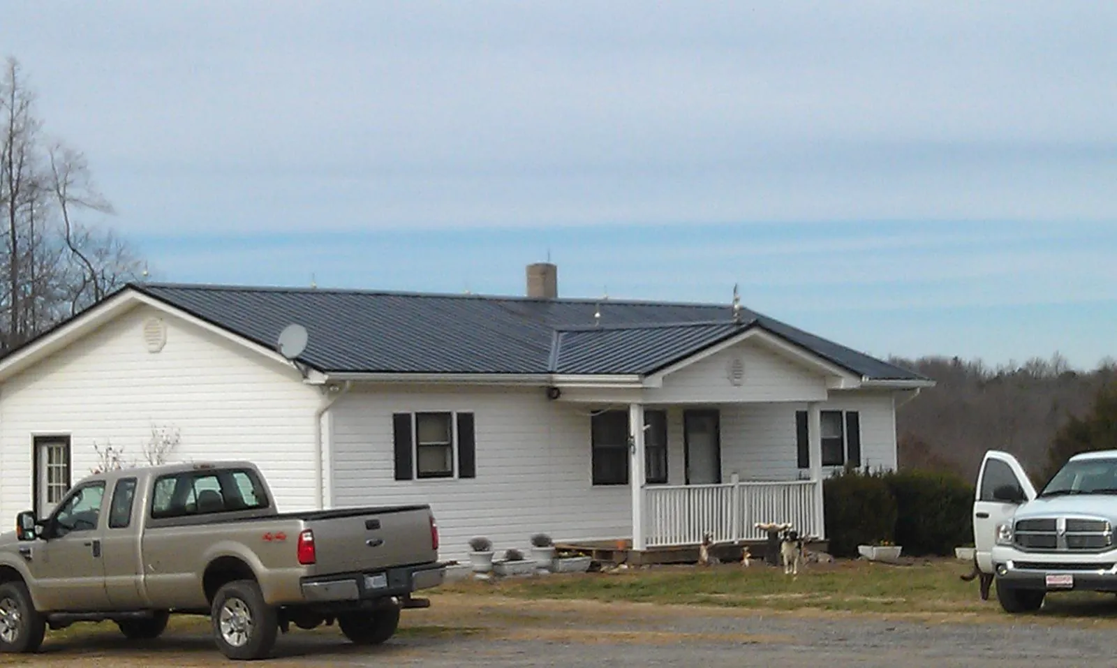 Finished dark metal roof on a white ranch home with work trucks parked in Oroville
