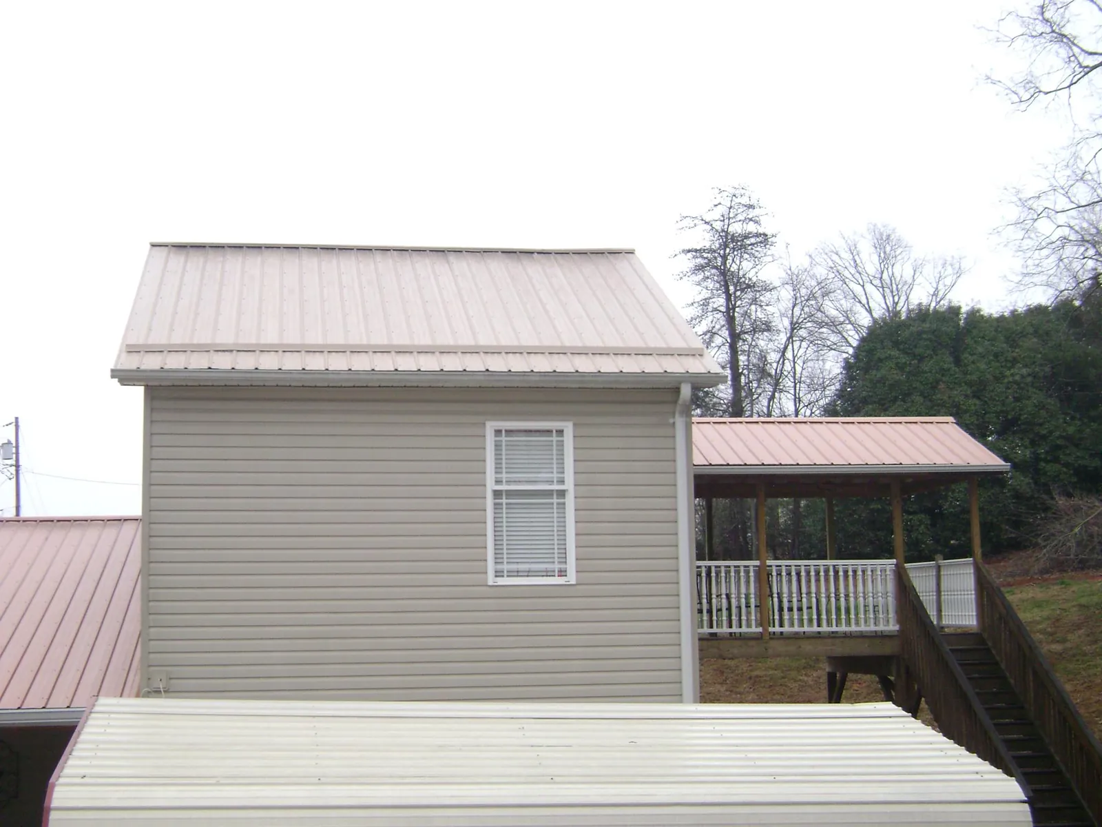 Tan metal roofs on a two story addition and attached porch, from a Roof Replacement job in Oroville